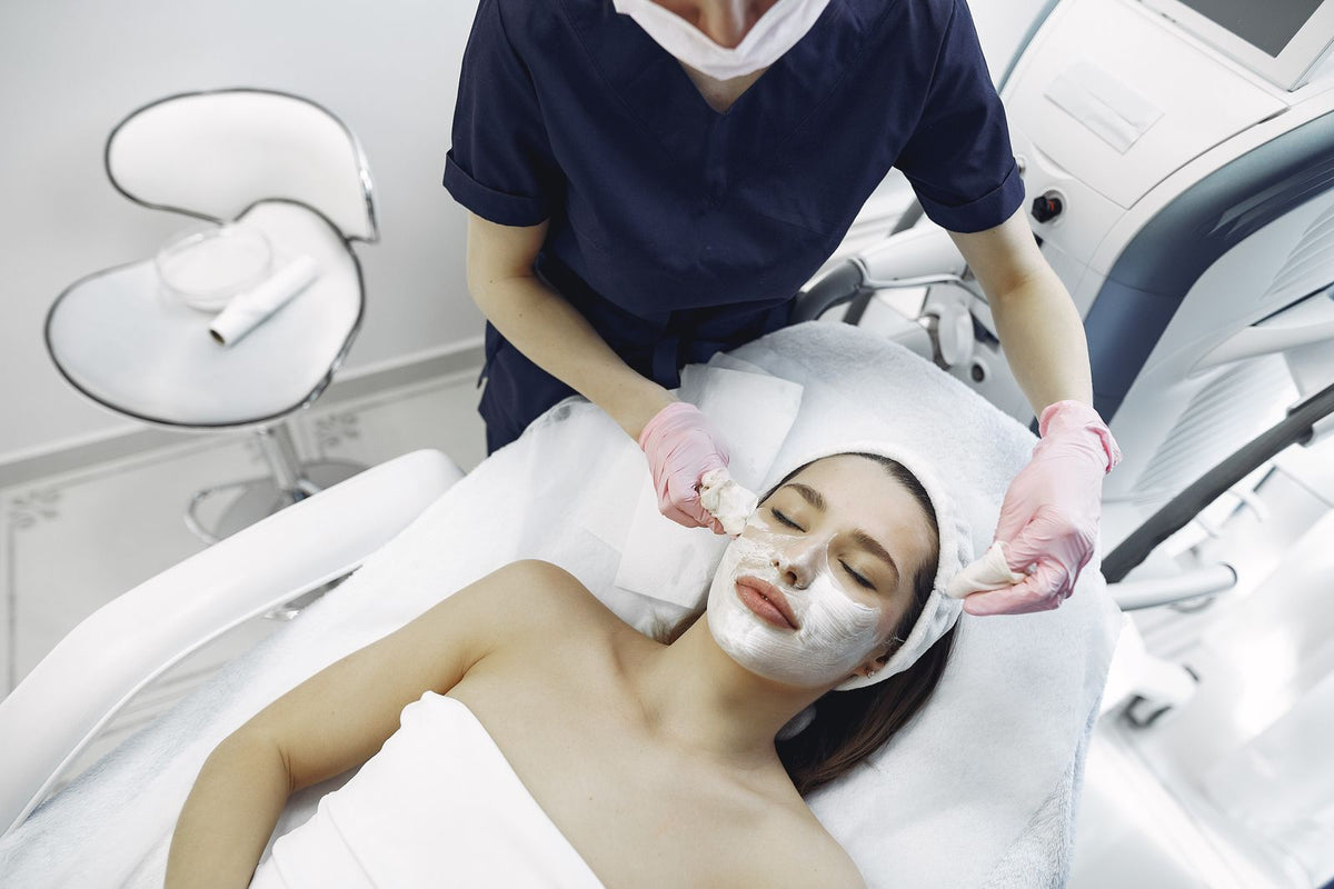 Esthetician removing a facial mask from a woman during a facial treatment